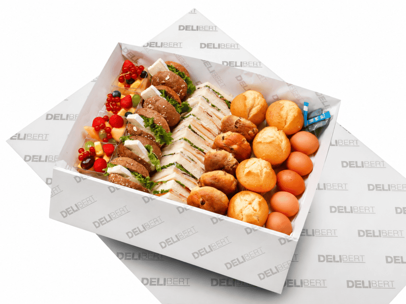 Uitgebreide ontbijtschaal met belegde broodjes, krentenbollen, muffins, gekookte eieren en fruitsalade.