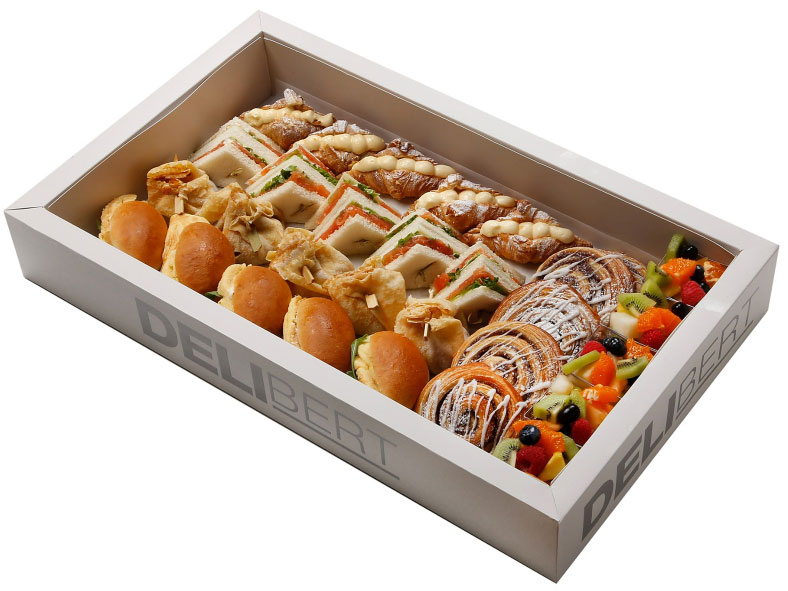 Luxe ontbijt- en lunchschaal met croissants, clubsandwiches, omelet, fruitsalade en zoete lekkernijen.